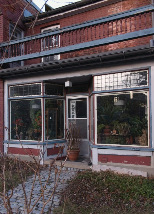 a brick building with three large windows and a small plant