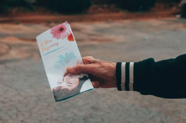 someone is holding a book on a beach