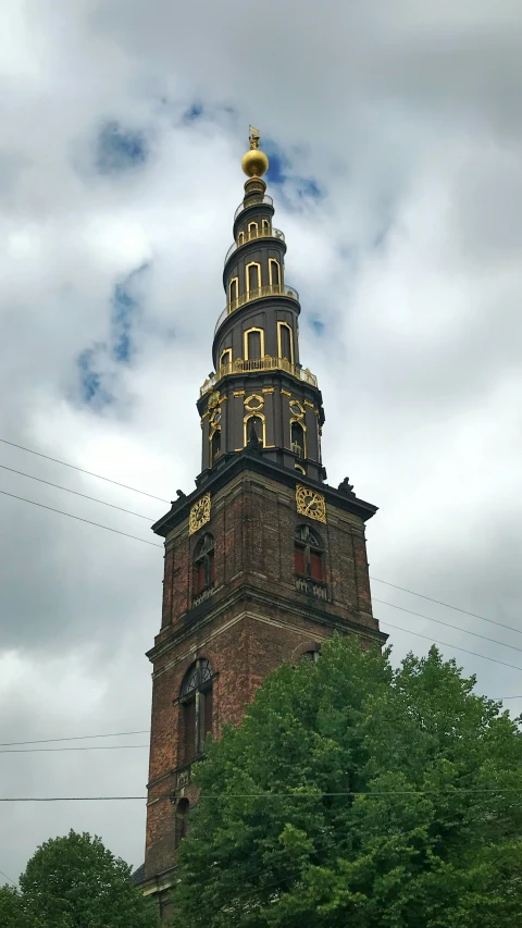 a tower with gold clocks on it near trees