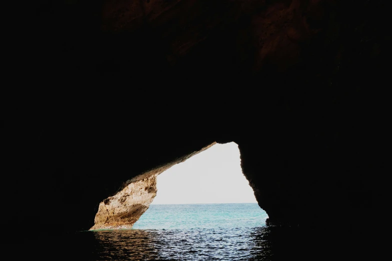 the inside of a cave with water in front of it