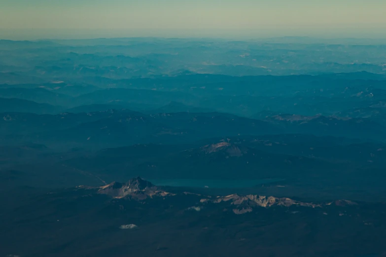 a very blue - toned view from an airplane as it flies over a mountain