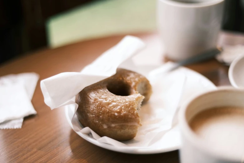 two donuts are sitting on top of napkins with coffee