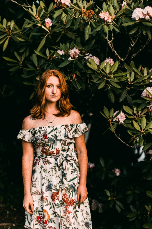 the woman is standing beneath a bush, outside