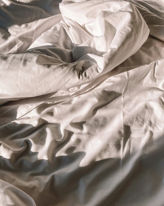 an up close view of a light colored sheet with white sheets