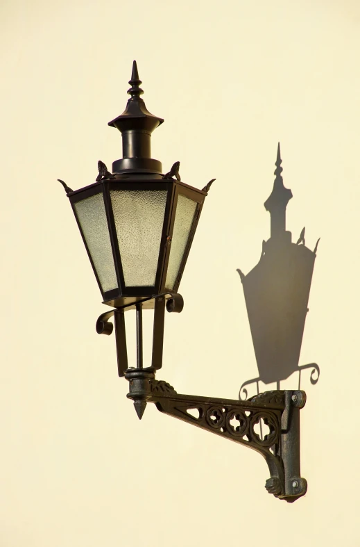 the shadow of an ornate street light and a decorative ornamental building