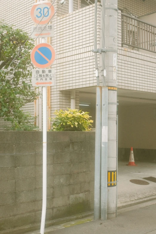 street signs on poles next to the sidewalk outside of a building