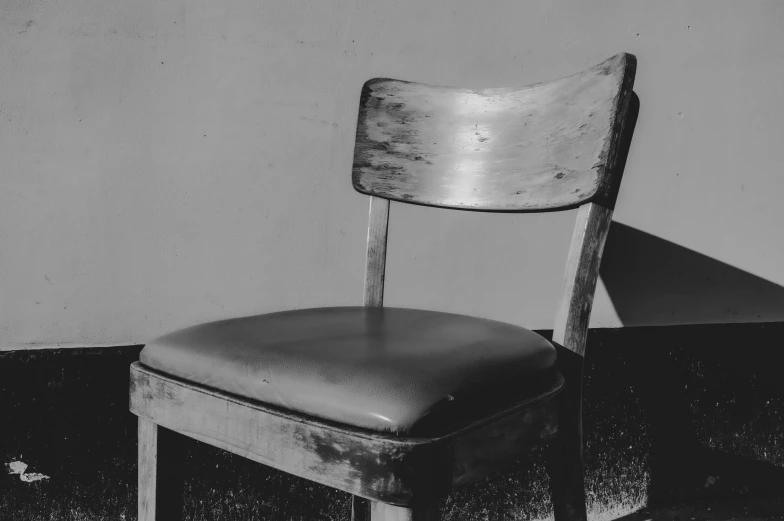 a chair in front of a wall and the back of a chair with leather seat