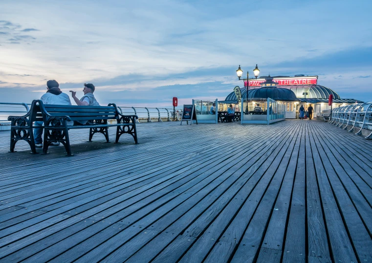 two people sitting on park benches watching the ocean