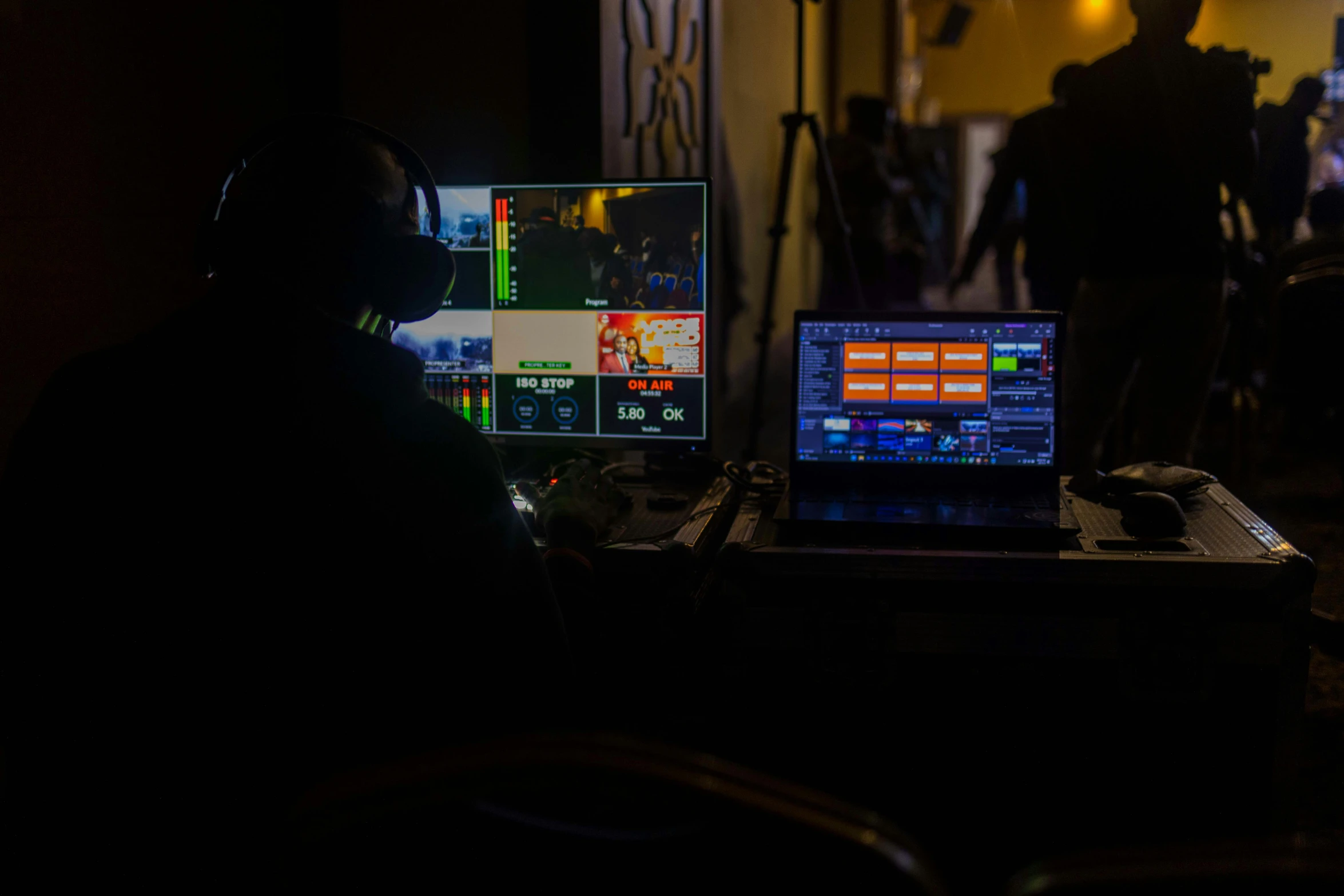 a laptop with two screens on the screen and people walking in the dark