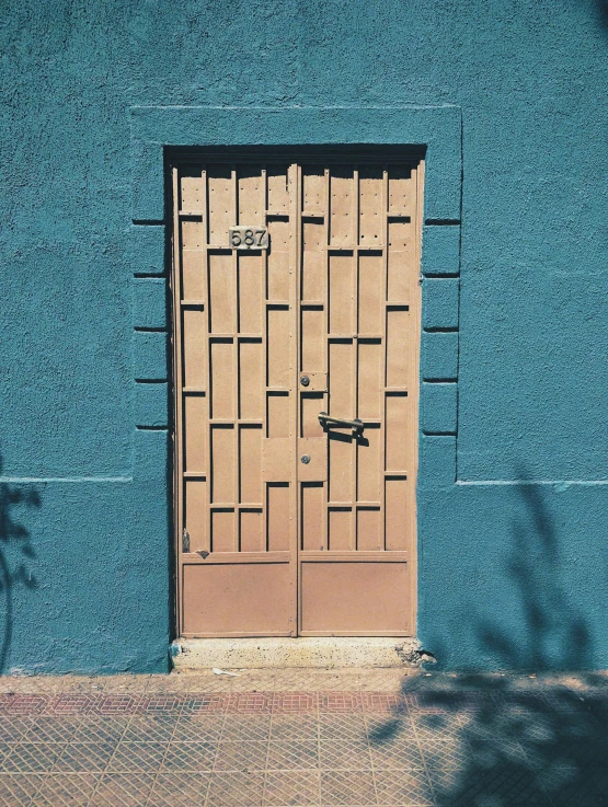 a large pair of wooden doors on a blue wall