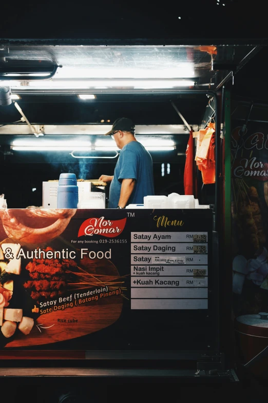 a man standing next to a sign for a food truck