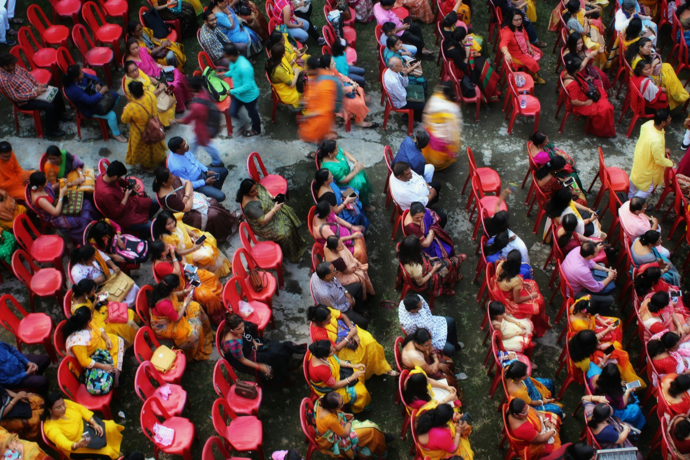 people sitting in red chairs in front of some other people