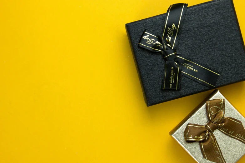 two gift wrapped in black paper with gold ribbon