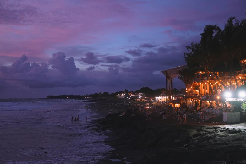 people stand on the shoreline next to the ocean at night