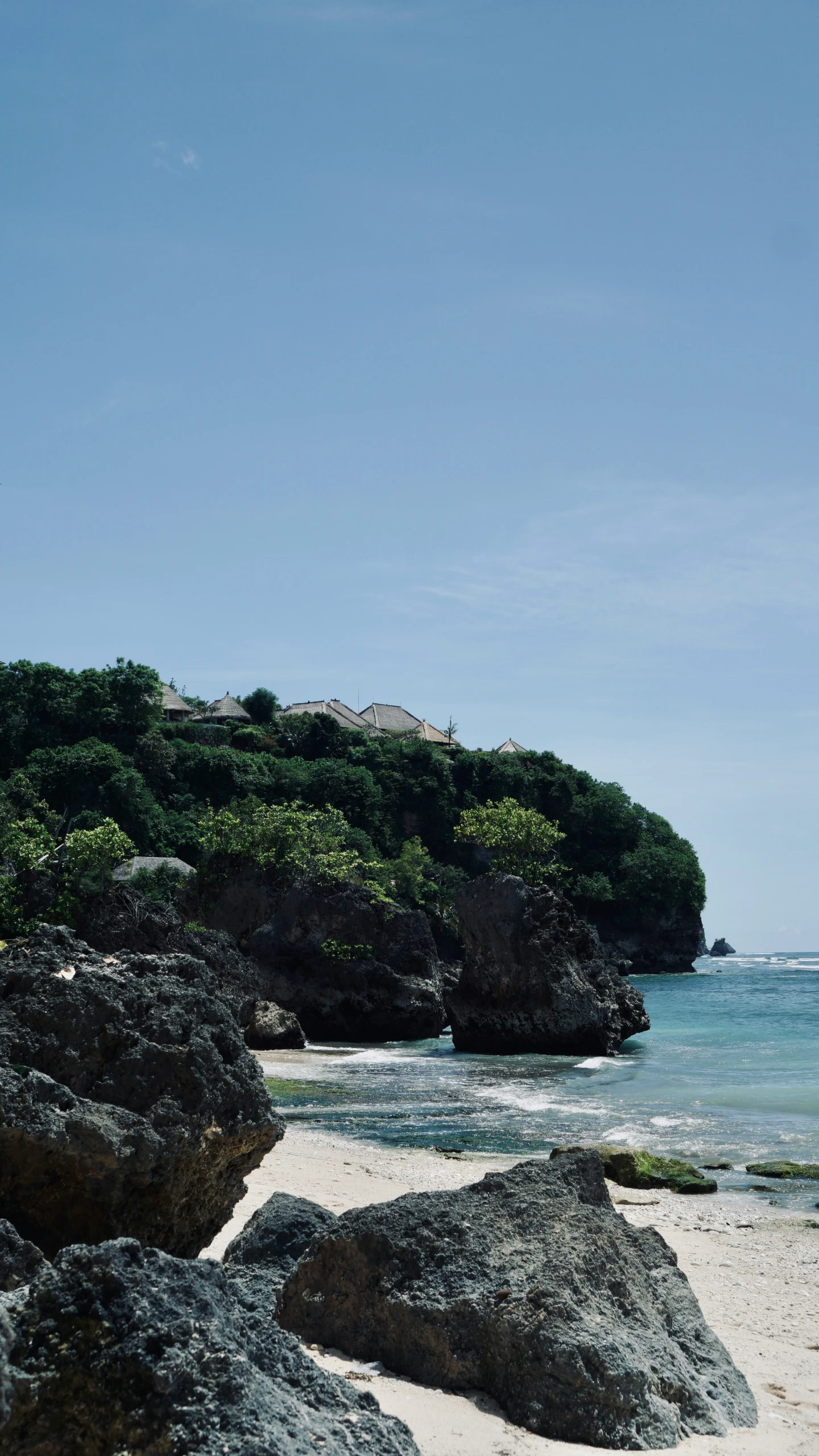 there is a large rock covered beach next to the ocean