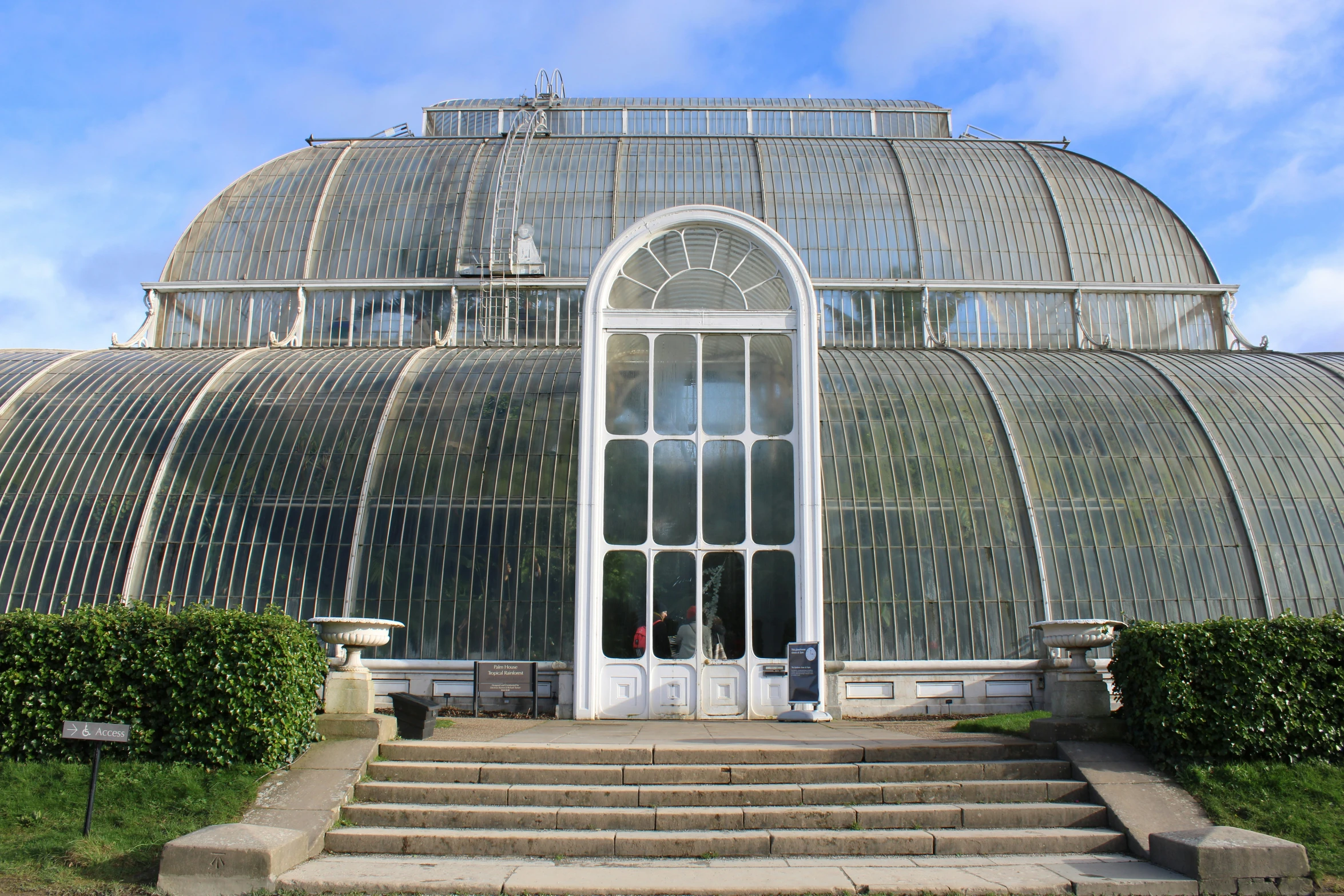 large glass greenhouse with a stairway in front