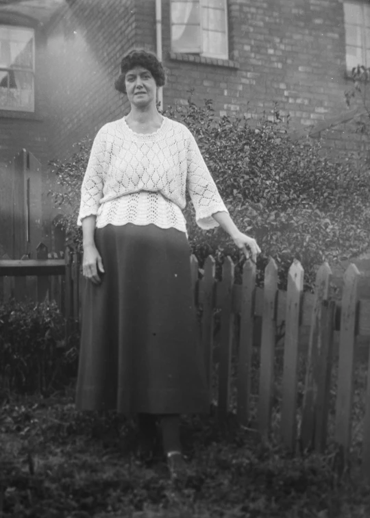 a woman posing for a po with an old brick building behind her