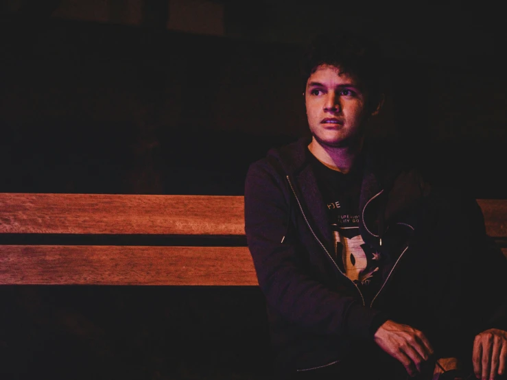 a man sitting on top of a wooden bench