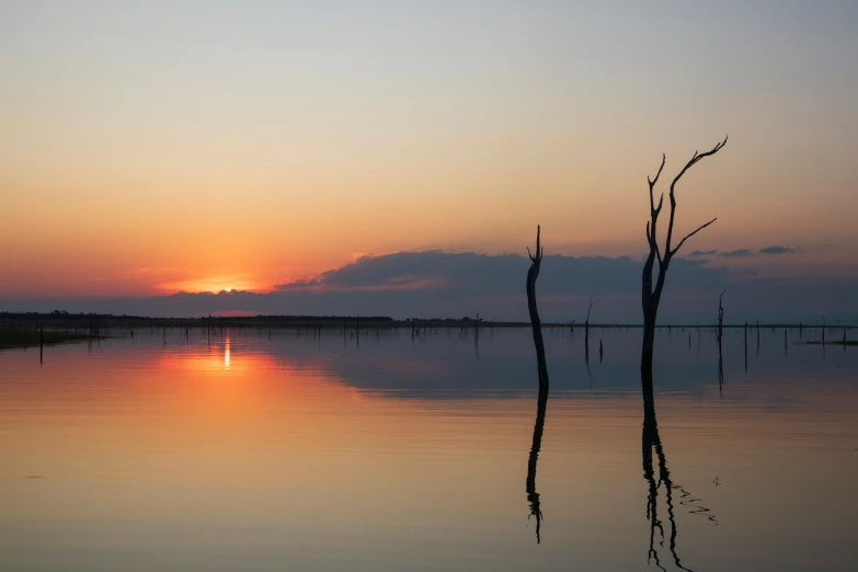 the sun sets over the horizon on the water