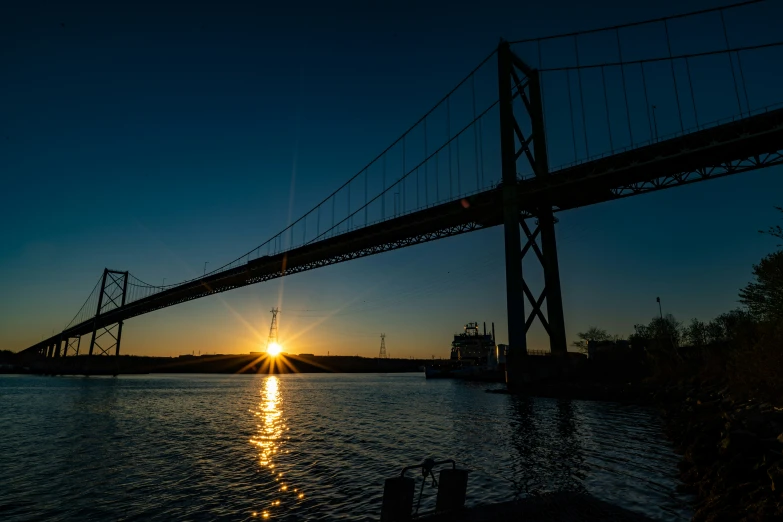 an old bridge with the sun setting behind it