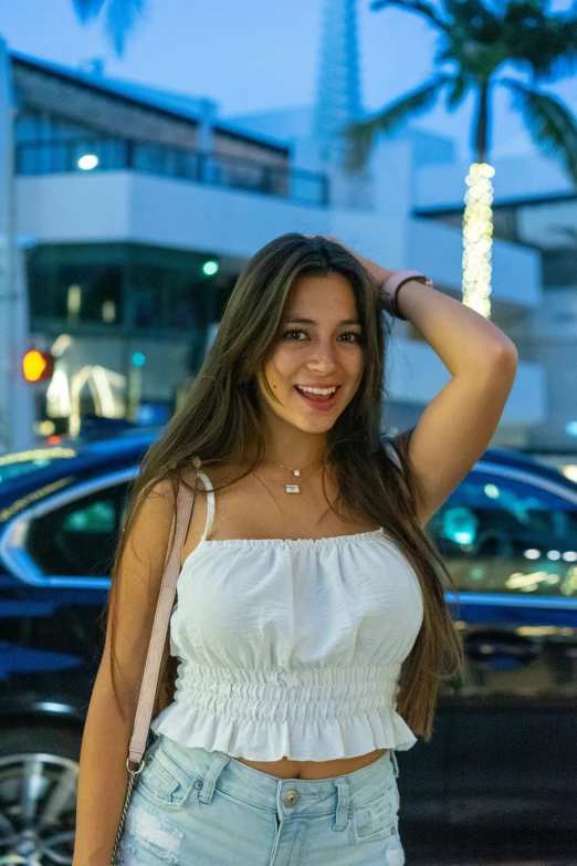 a woman in a white top standing next to a car