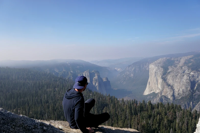 a man sitting on a mountain above a valley