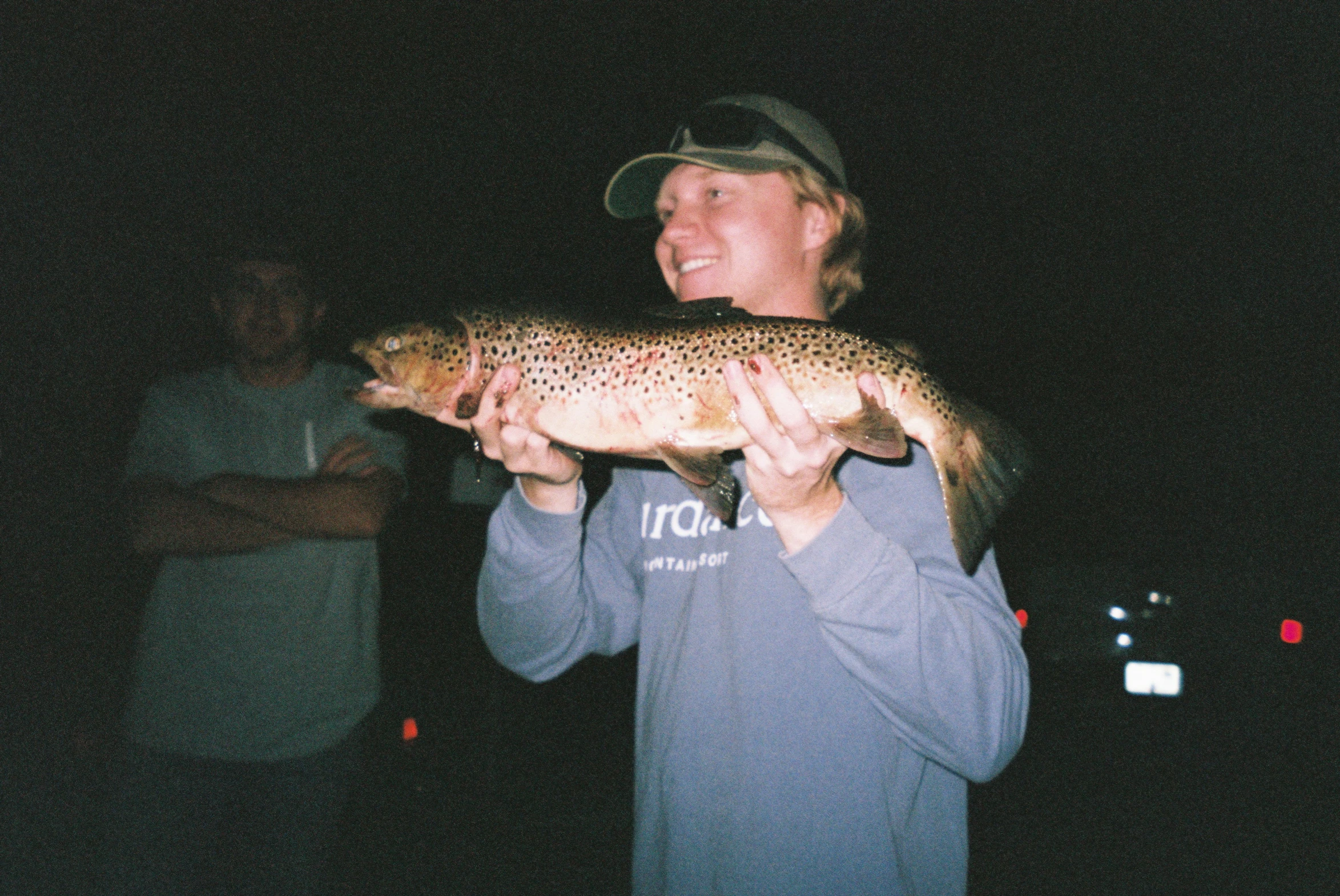 a man standing in front of a truck while holding a fish