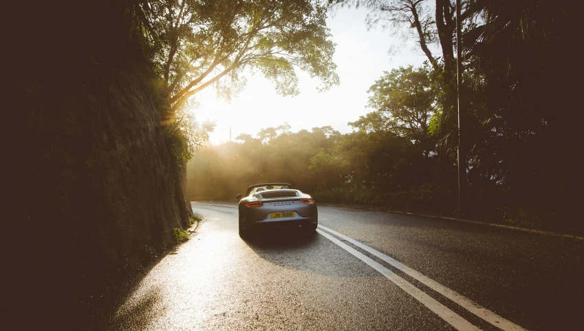 there is a car going down the road with a sunset in the background