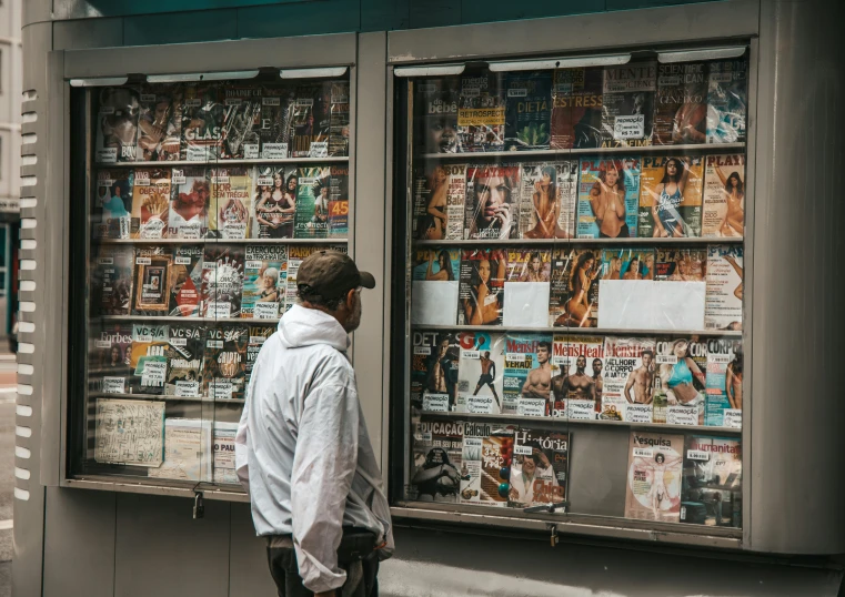 a man is standing in front of a newspaper shop