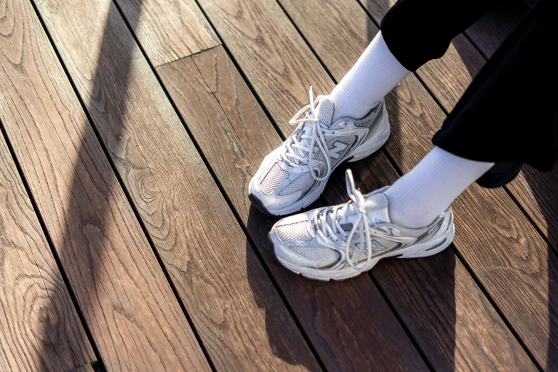 a person wearing athletic shoes standing on a wooden floor