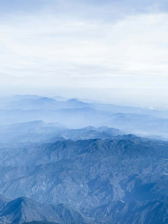 an airplane flying over mountains on a cloudy day