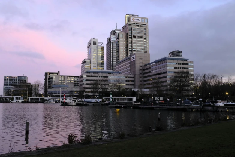 the buildings are all beside the river at twilight