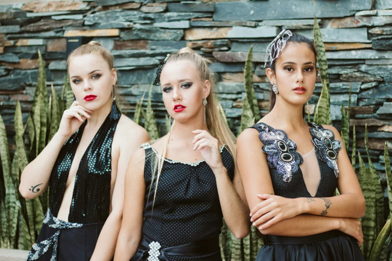 three young women in black dresses and red lipstick