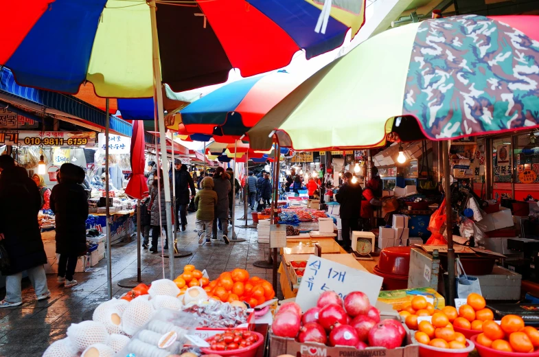 fruit is displayed under open umbrellas at an outdoor market