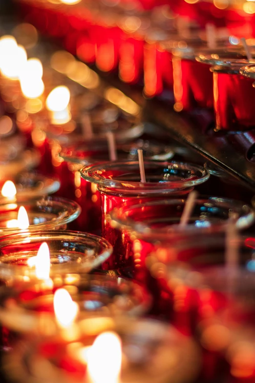 candles are on a row and lit, reflecting off the others