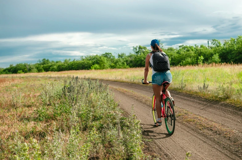 a woman riding a bike down a dirt road