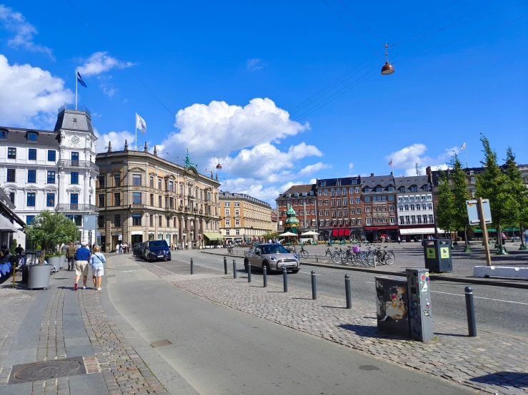 the city is busy with people, parked cars and several buildings