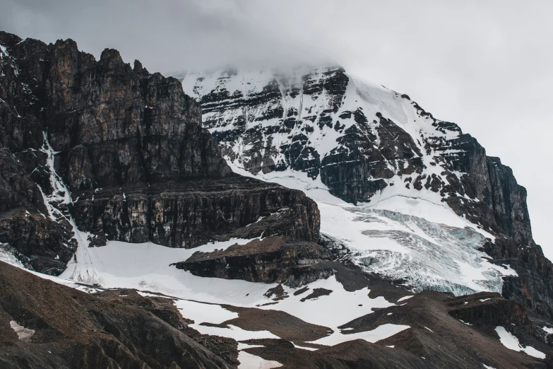 a snowy mountain with large rocks and some clouds