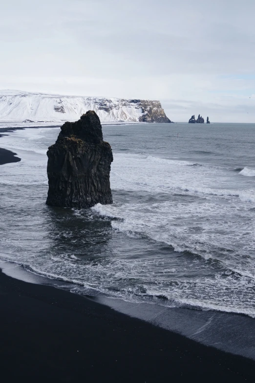 black sand beach and a black rock out in the water