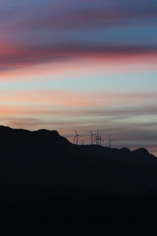 a view of a hill with wind mills in the distance