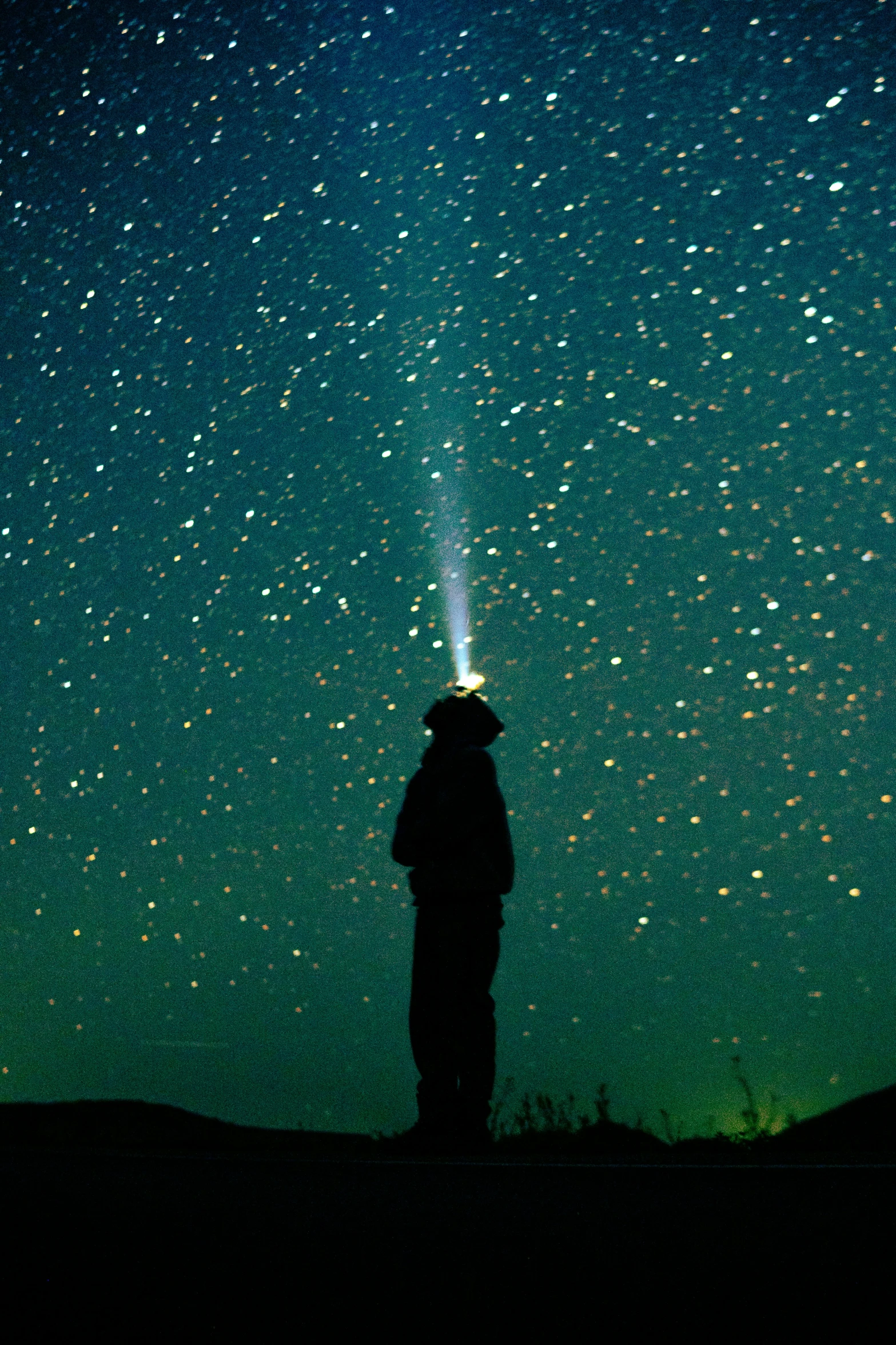 silhouette of a person with an flashlight standing in the night sky