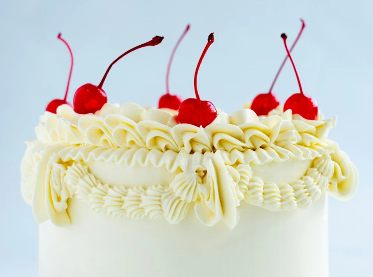 a three layer cake decorated with white frosting and cherries