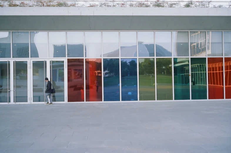 a man is walking past a row of large windows