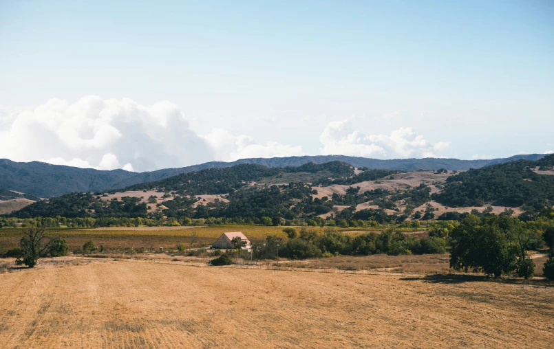 a mountain range with trees and a lone barn