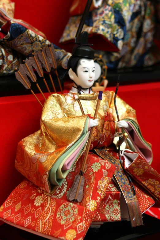 a doll in a costume holding arrows and two other figurines