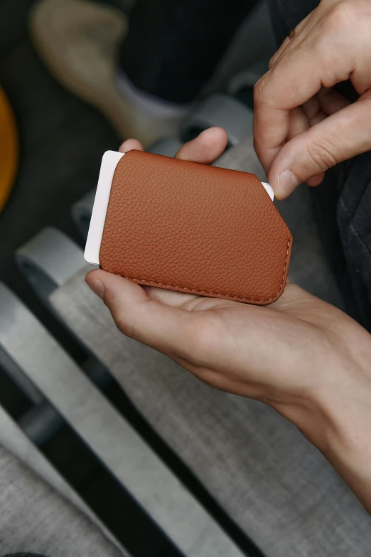 a person holding onto a leather case with his fingers