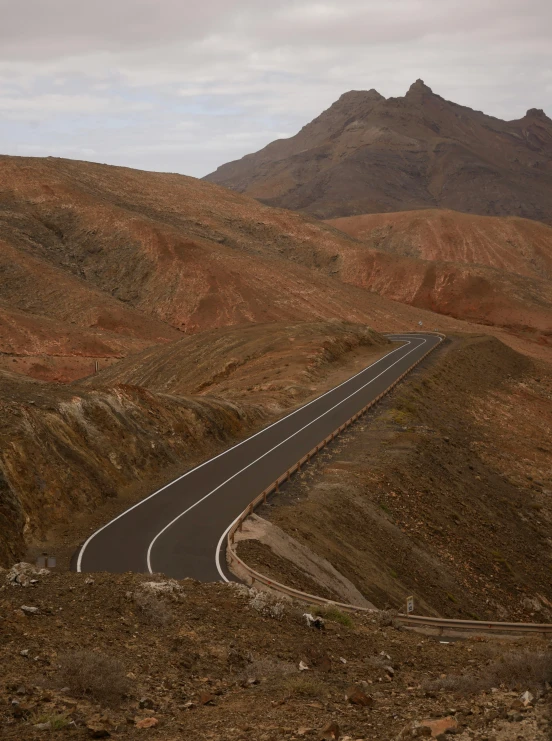 a road winding the middle of the desert with hills in the background