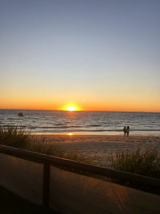 the sun sets on a beach with two people riding a horse