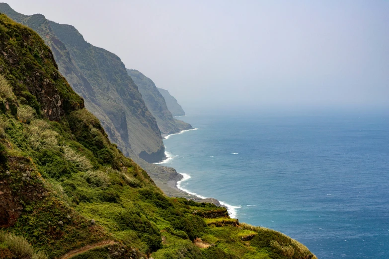 the ocean and mountains is very tall with a path going up it