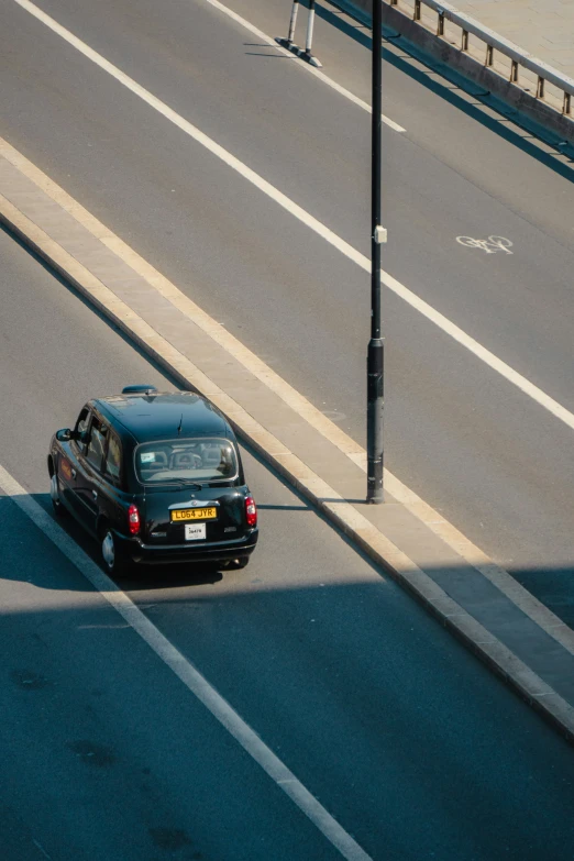 black car driving down road next to a tall pole